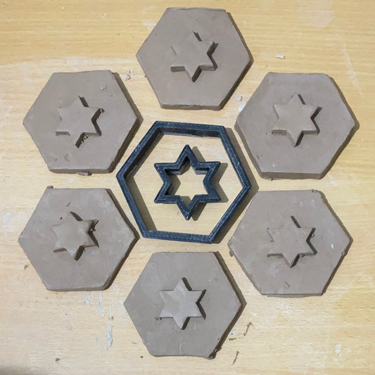 Two clay cutters (a hexagon and star shape) surrounded by 6 hexagons and stars cut from stoneware clay.